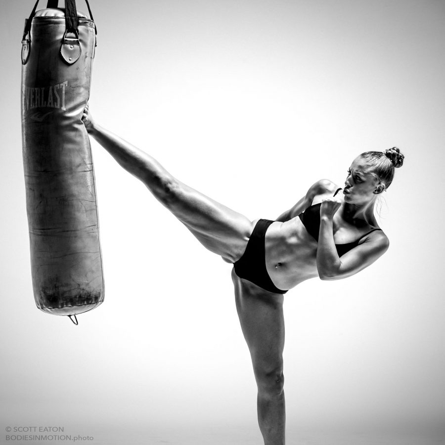 female kickboxer doing a high kick on a punching bag